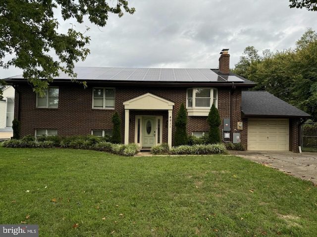 split foyer home featuring solar panels, a front yard, and a garage