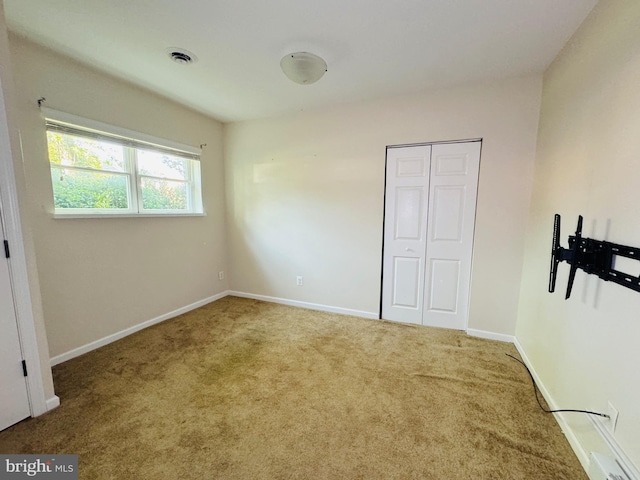 unfurnished bedroom featuring baseboards, visible vents, carpet, and a closet