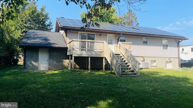 rear view of house featuring stairway, a lawn, central air condition unit, solar panels, and a wooden deck