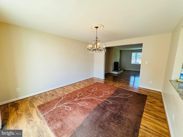unfurnished dining area featuring wood finished floors, a notable chandelier, and baseboards