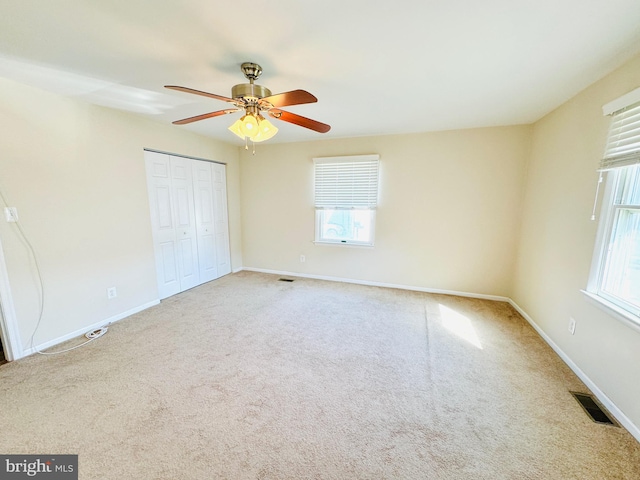 unfurnished bedroom with a closet, ceiling fan, multiple windows, and carpet floors