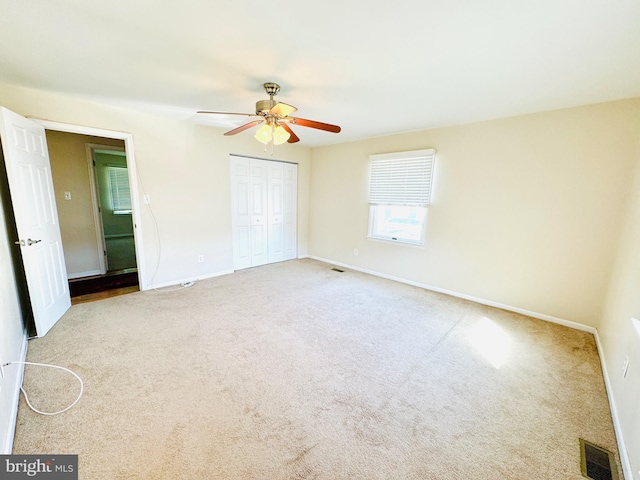 unfurnished bedroom featuring ceiling fan, carpet, a closet, visible vents, and baseboards