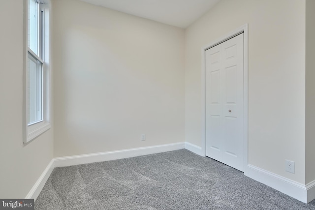 unfurnished bedroom with a closet, multiple windows, and carpet floors