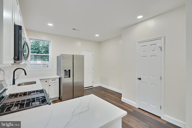 kitchen with light stone counters, white cabinetry, dark wood-type flooring, sink, and stainless steel appliances