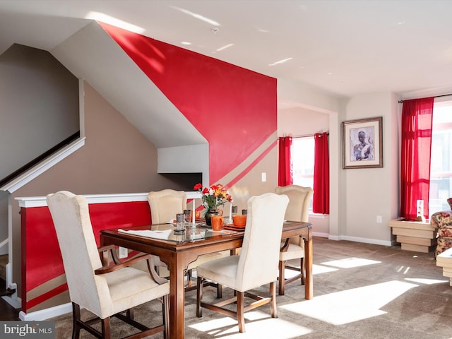 carpeted dining space featuring vaulted ceiling