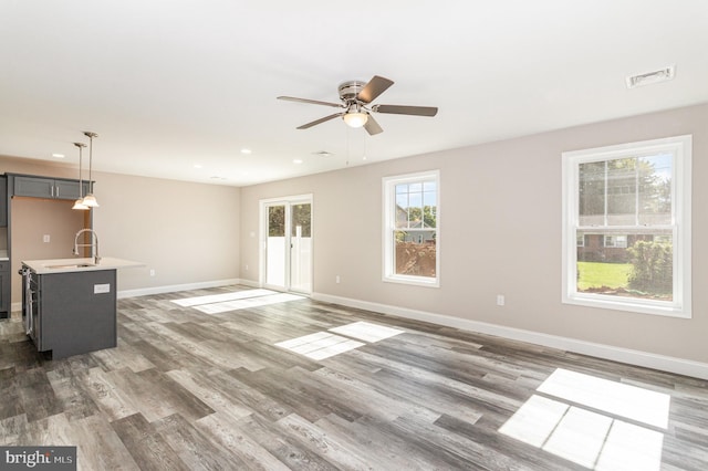 unfurnished living room with dark hardwood / wood-style floors, ceiling fan, and sink