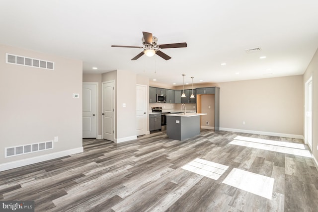 unfurnished living room with ceiling fan, sink, and hardwood / wood-style floors