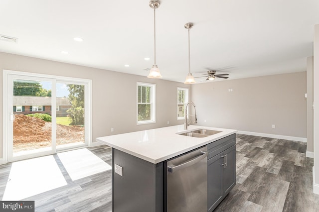 kitchen featuring stainless steel dishwasher, ceiling fan, a kitchen island with sink, sink, and decorative light fixtures