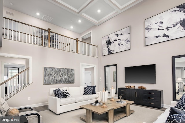 living room with a towering ceiling, hardwood / wood-style floors, beamed ceiling, and coffered ceiling