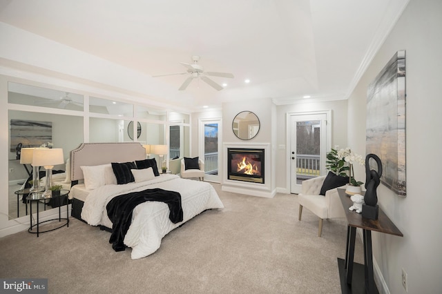 carpeted bedroom featuring ceiling fan, access to exterior, crown molding, and a tray ceiling