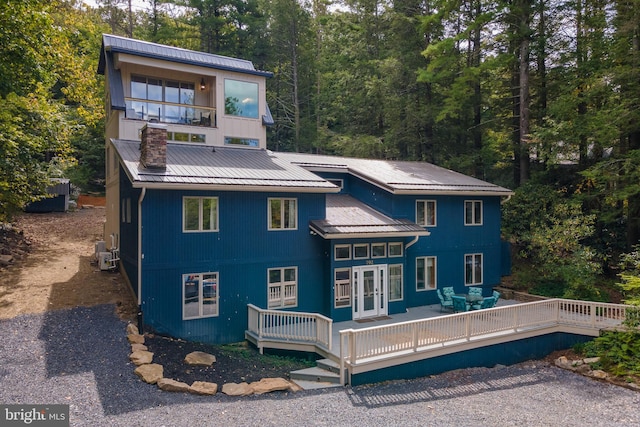 back of house with french doors, a balcony, and a deck