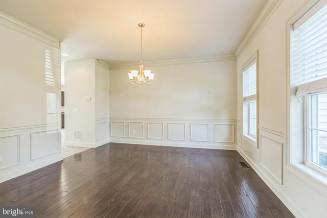 unfurnished dining area with an inviting chandelier, dark hardwood / wood-style floors, and ornamental molding