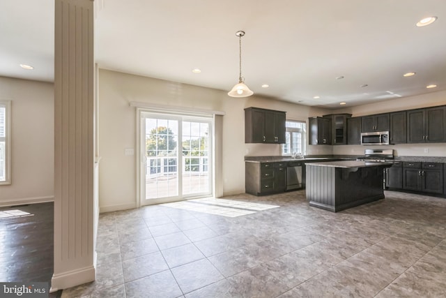 kitchen featuring appliances with stainless steel finishes, dark brown cabinets, pendant lighting, and a center island