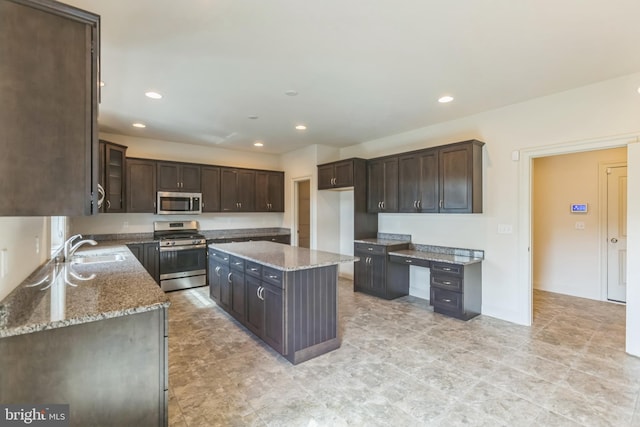 kitchen featuring a kitchen island, light stone counters, dark brown cabinetry, stainless steel appliances, and sink