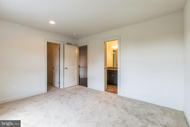 unfurnished bedroom with light colored carpet and ensuite bathroom