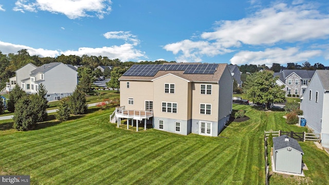 rear view of property with solar panels and a yard