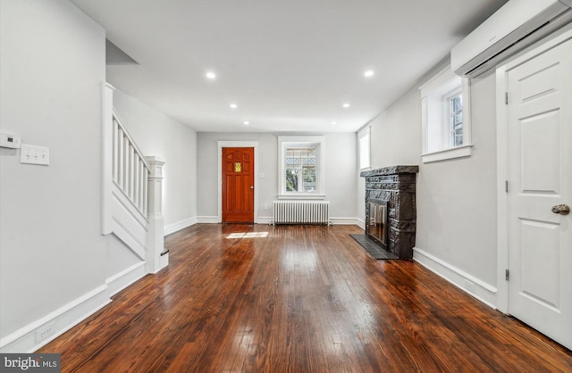 entryway featuring a fireplace, radiator heating unit, an AC wall unit, and dark hardwood / wood-style flooring