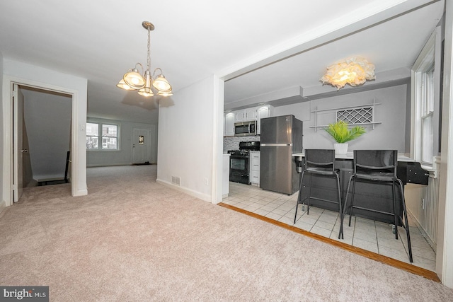 kitchen with pendant lighting, visible vents, stainless steel appliances, an inviting chandelier, and light carpet