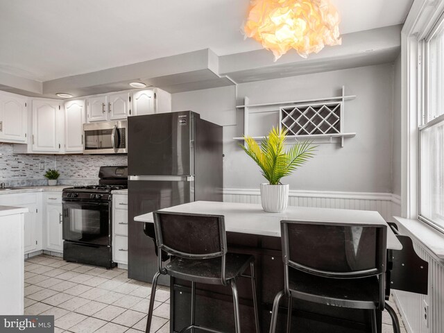 kitchen with light tile patterned floors, white cabinetry, a chandelier, stainless steel appliances, and light countertops