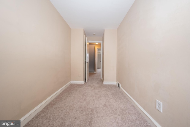 corridor featuring light colored carpet, visible vents, and baseboards