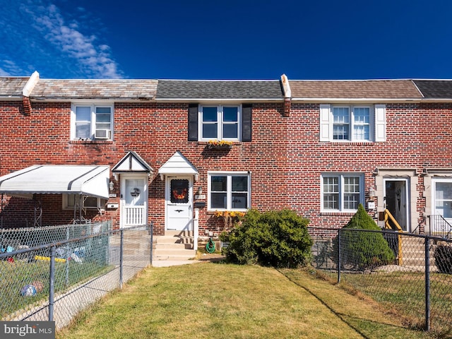 multi unit property with brick siding, fence private yard, entry steps, cooling unit, and a front yard