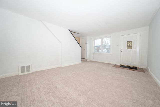 carpeted entrance foyer with baseboards, visible vents, and stairs