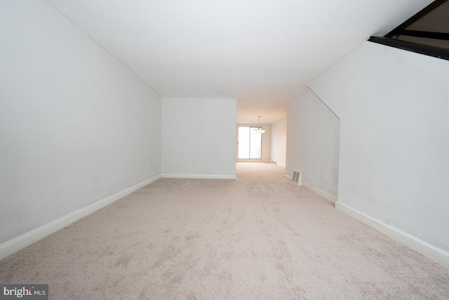 additional living space featuring baseboards, visible vents, an inviting chandelier, and carpet