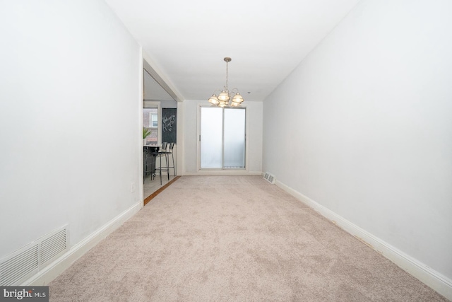 carpeted spare room with baseboards, visible vents, and a notable chandelier