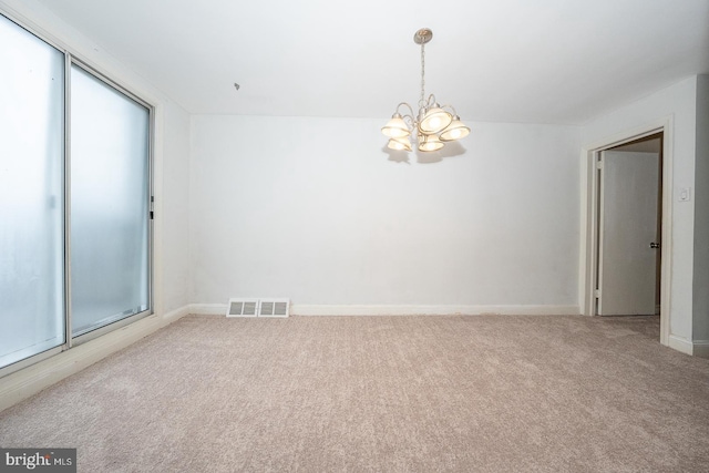 empty room featuring carpet flooring, a notable chandelier, visible vents, and baseboards
