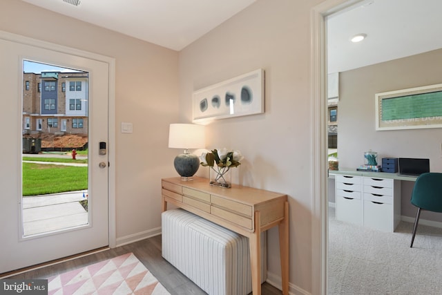 doorway featuring light wood-type flooring and built in desk