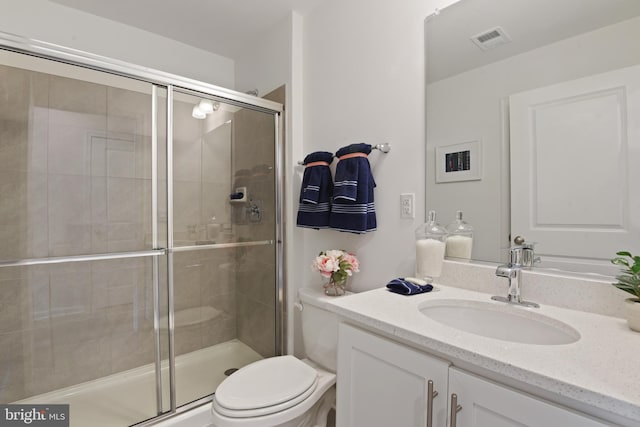 bathroom featuring a shower with shower door, vanity, and toilet