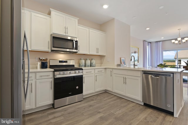 kitchen with light wood-type flooring, stainless steel appliances, white cabinets, sink, and kitchen peninsula