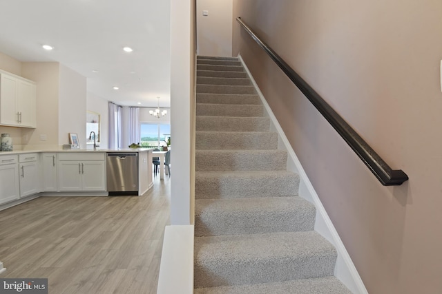 stairway with a notable chandelier and hardwood / wood-style floors