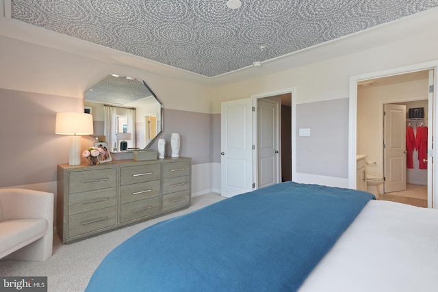 bedroom featuring ensuite bathroom and light carpet