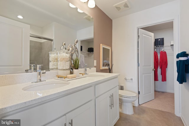 bathroom with toilet, tile patterned flooring, vanity, and a shower with shower door