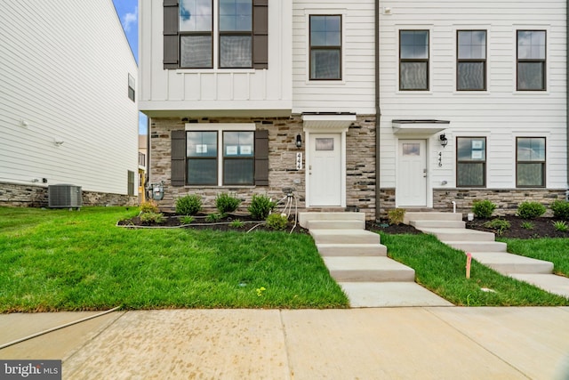 view of front of property with central air condition unit and a front yard