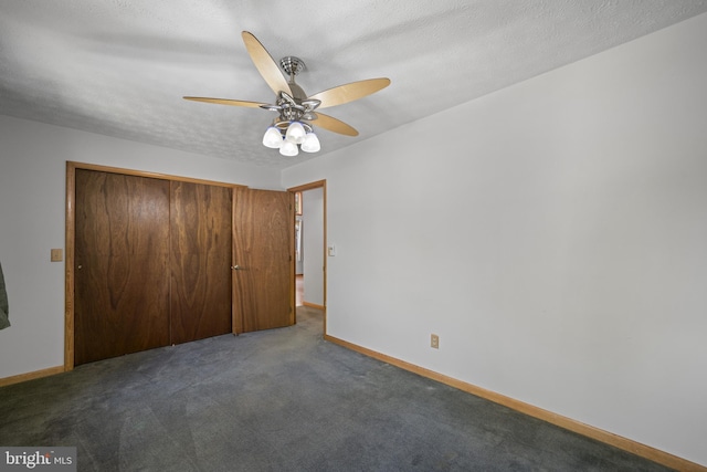 unfurnished bedroom with ceiling fan, a textured ceiling, a closet, and dark colored carpet