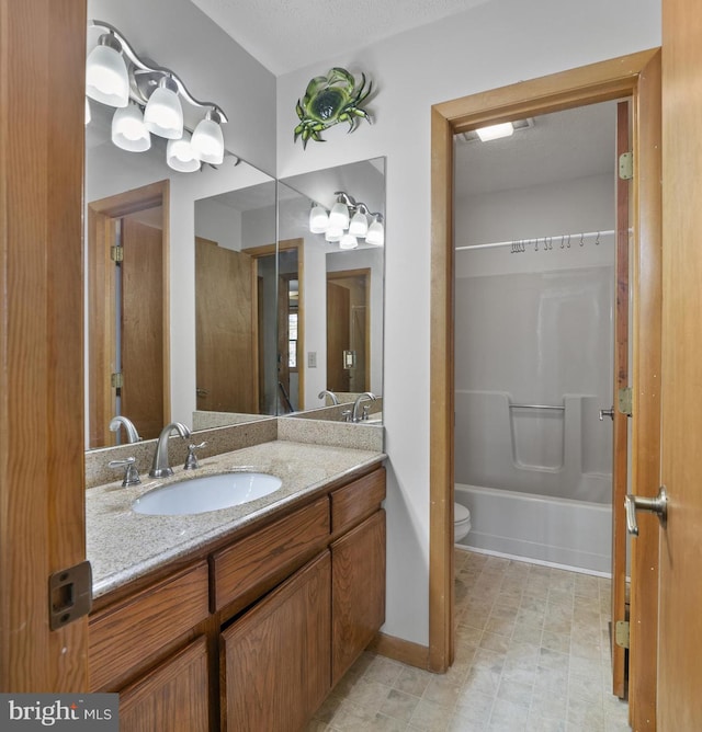 full bathroom with vanity, bathtub / shower combination, toilet, and a textured ceiling