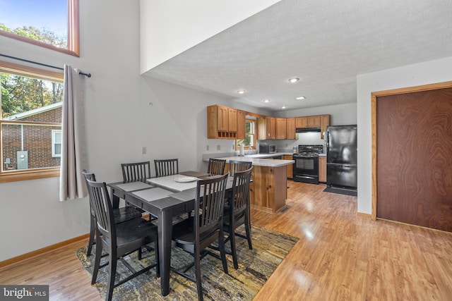 dining area featuring a textured ceiling, sink, and light hardwood / wood-style floors