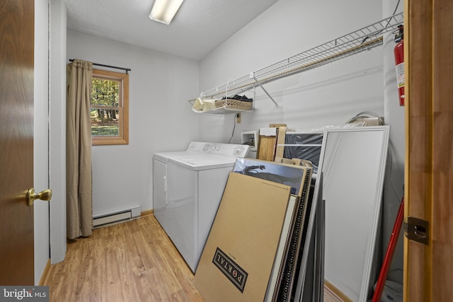 clothes washing area with baseboard heating, independent washer and dryer, and light hardwood / wood-style flooring