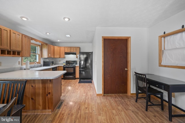 kitchen featuring light hardwood / wood-style flooring, sink, kitchen peninsula, black appliances, and a textured ceiling