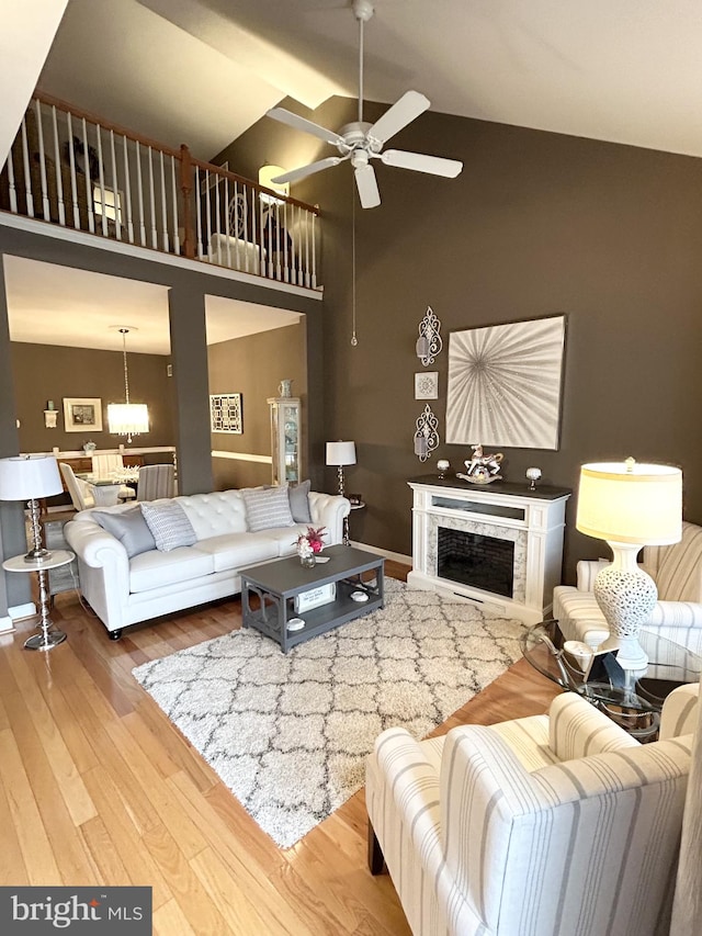 living room featuring ceiling fan with notable chandelier, high vaulted ceiling, and hardwood / wood-style flooring