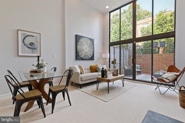 carpeted living room featuring floor to ceiling windows and a towering ceiling