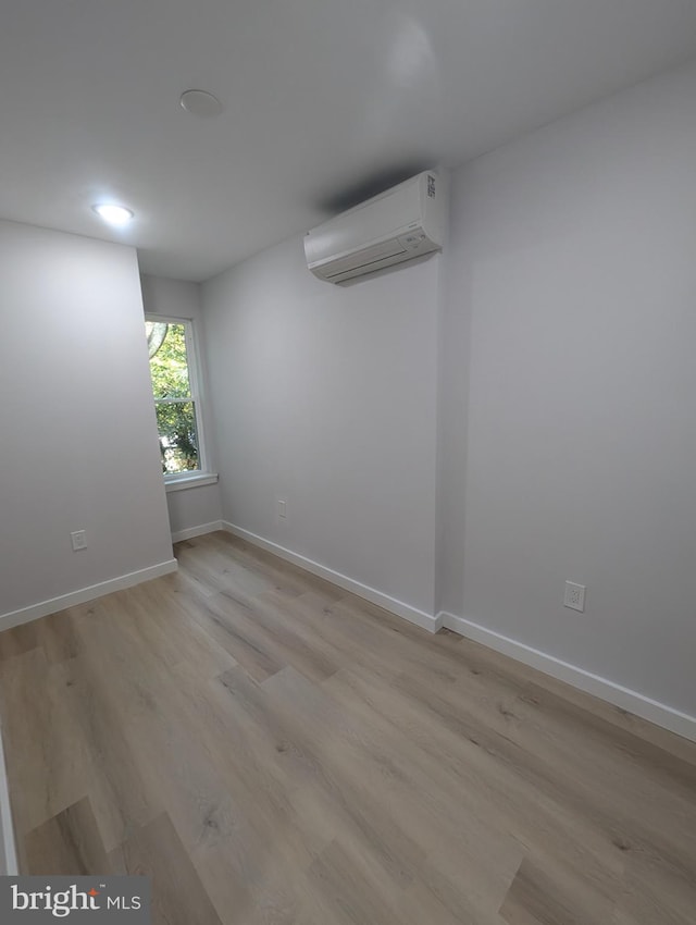 unfurnished room with light hardwood / wood-style flooring and a wall unit AC