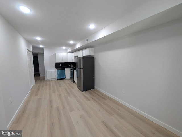 kitchen with appliances with stainless steel finishes, white cabinetry, sink, and light hardwood / wood-style floors