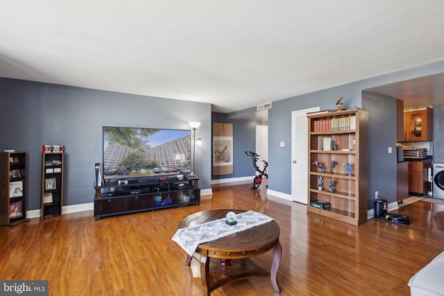 living room with wood-type flooring and washer / dryer