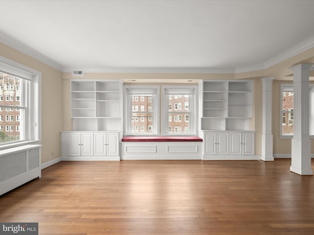 unfurnished living room featuring decorative columns, wood finished floors, visible vents, and ornamental molding