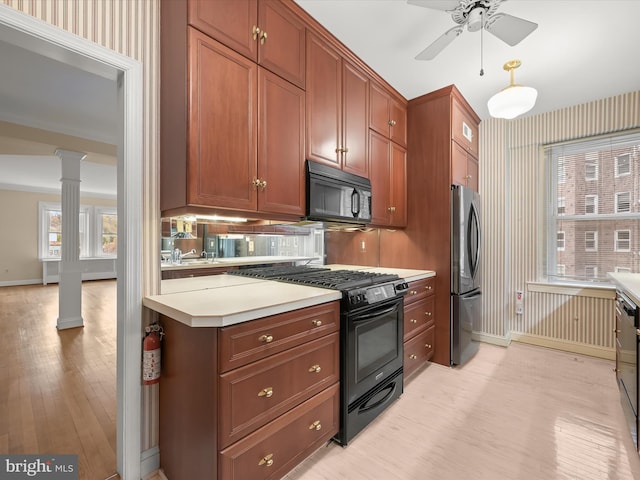 kitchen featuring brown cabinets, black appliances, light countertops, and ornate columns