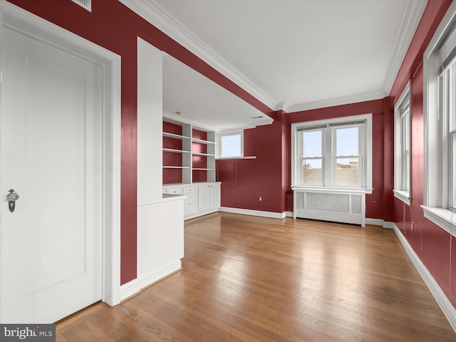 unfurnished living room with built in features, wood finished floors, baseboards, and ornamental molding