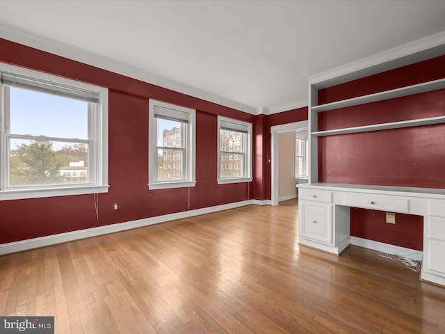 unfurnished office featuring baseboards, wood-type flooring, and built in study area